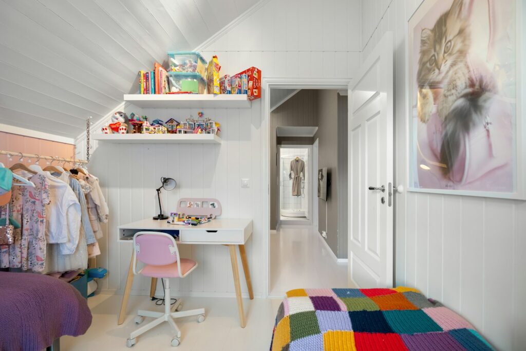 A bedroom with a bed, desk, and shelves